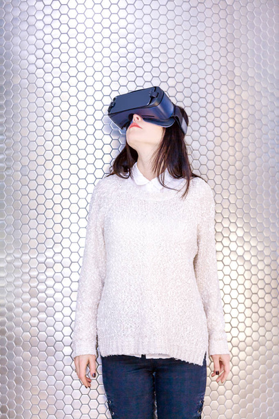 Uma jovem com um fone de ouvido no rosto encontra novas tecnologias. Mulher usando headset realidade virtual
. - Foto, Imagem