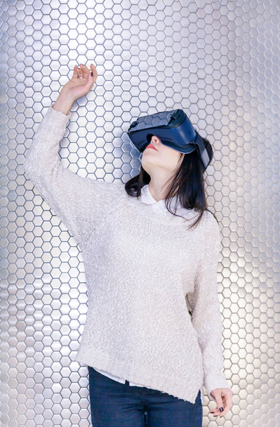 ein junges Mädchen mit einem Headset im Gesicht trifft auf neue Technologien. Frau mit Virtual-Reality-Headset. - Foto, Bild