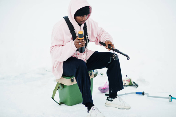 African american fisherman with fishing rod and thermos. Winter fishing. - Foto, Bild
