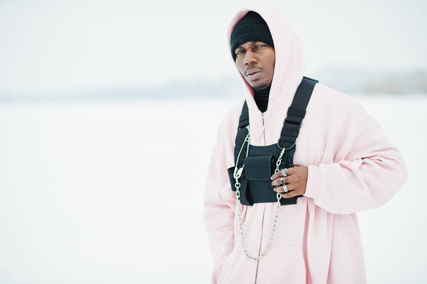 Stylish urban style african american man in pink hoodie posed at frozen lake in winter. - Fotó, kép