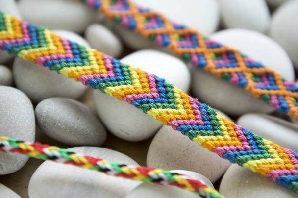 Bracelets of friendship, colorful woven friendship bracelets on white pebbles, white sea pebble stones, rainbow colors - Photo, Image