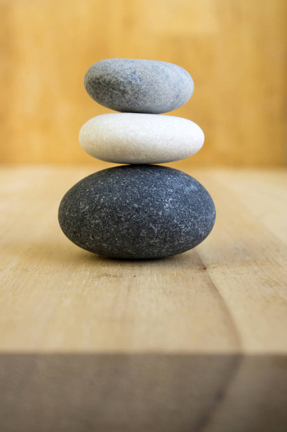 Harmony and balance, poise stones on wooden table, rock zen sculpture, five dark grey and white pebbles, cairns, bicolor, two colors - black and white - 写真・画像