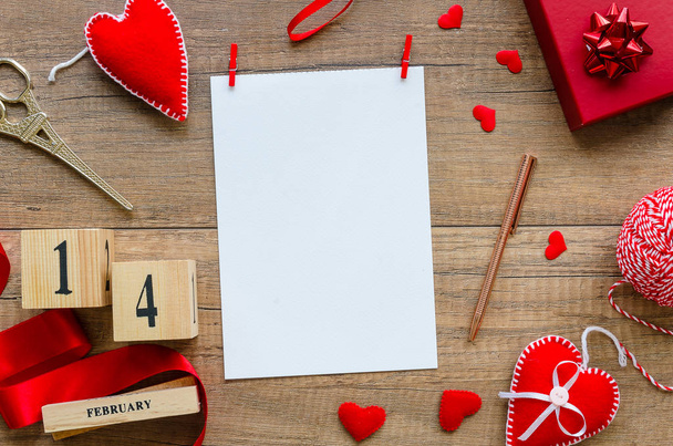Valentines day mockup. Flat lay composition from red hearts, ribbon, perpetual calendar date 14 february, gift box, pen on wooden background with blank paper sheet a5. Saint Valentine day decoration - Φωτογραφία, εικόνα