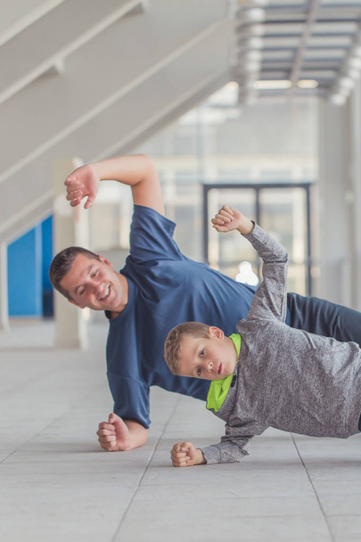 Little boy and his father exercising together at a sports center. Father and son spend time together and lead a healthy lifestyle.Working Out Together. Fitness Day. Sporty Family Concept. Active Lifestyle - Fotoğraf, Görsel
