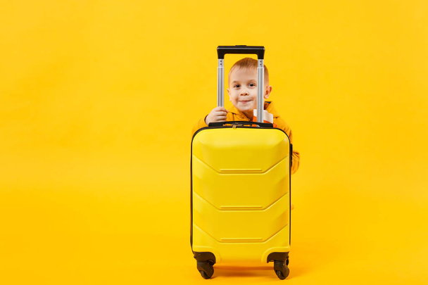 Маленький путешественник турист мальчик 3-4 лет изолирован на желтой оранжевой стене фоновой студии. Пассажир, путешествующий за границу в выходные дни отдыха. Концепция полёта. Макет копировального пространства
 - Фото, изображение