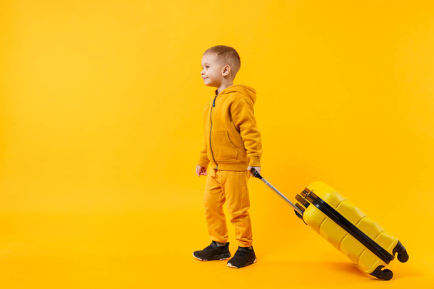 Маленький мандрівник-туристичний хлопчик 3-4 роки ізольований на жовтій оранжевій стіні фонової студії. Пасажири, які виїжджають за кордон у відпустку у вихідні дні. Концепція авіаперельоту. Простір копіювання макетів
 - Фото, зображення