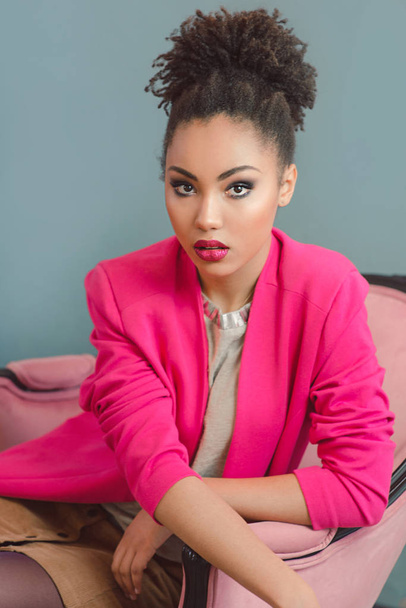 beautiful attractive young woman (mixed rase) with make up and in pink blazer sitiing on the chair - Foto, immagini
