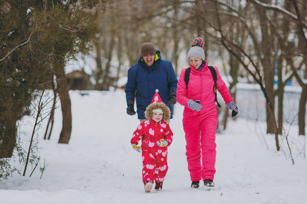 Onnellinen perhe nainen, mies ja pieni tyttö lämpimissä vaatteissa käynnissä, kävely luminen puistossa tai metsässä ulkona. Talvi hauskaa, vapaa lomilla. Rakkaus lapsuuden suhde perhe ihmiset elämäntapa käsite
 - Valokuva, kuva