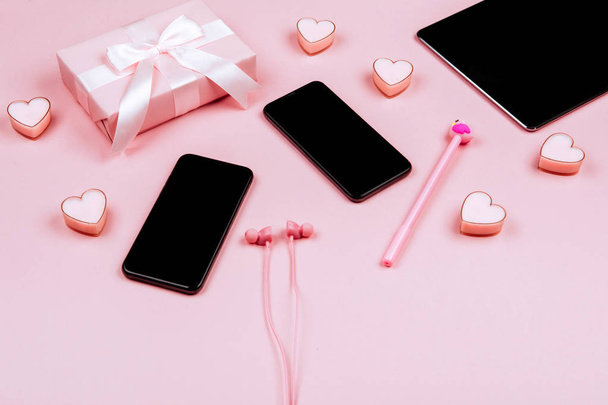 Smartphone, laptop, gifts, headphones and female accessories on pink background. Event concept - Photo, image