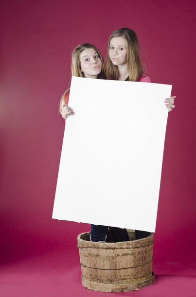 muotokuva tytöistä seisoo tynnyri ja tilalla tyhjä juliste
 - Valokuva, kuva