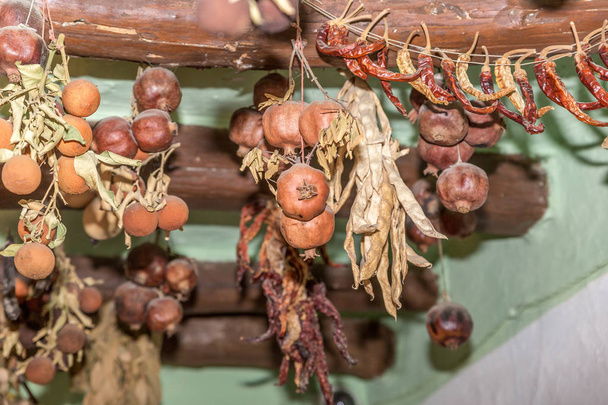 Frutas y verduras secas colgadas de un viejo techo de madera, en un gran patio de un pueblo en España
 - Foto, Imagen