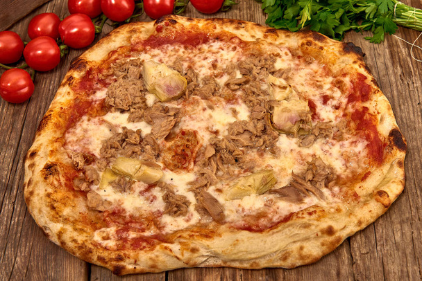 Pizza gourmet fresca casera con ajo, atún y alcachofas, Pizza italiana sabrosa aislada en mesa de madera, Primer plano con enfoque selectivo
 - Foto, imagen