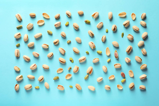 Composition with organic pistachio nuts on color background, flat lay - Zdjęcie, obraz