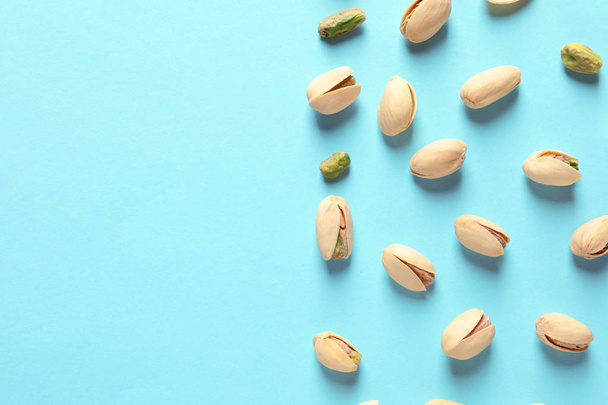 Composition with organic pistachio nuts on color background, flat lay. Space for text - Foto, Imagen