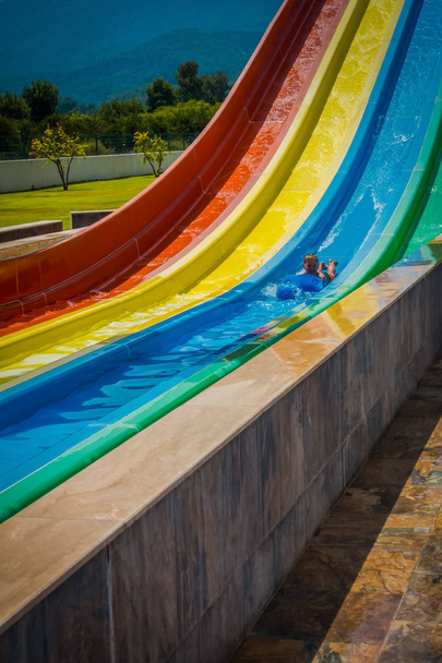 Chłopiec jeździ do slajdu w parku wodnego - Zdjęcie, obraz