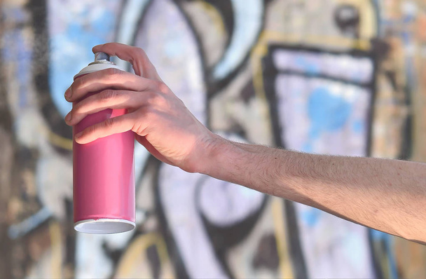 Φωτογραφία του χεριού του street artist που αντλεί μια νέα εικόνα χρώμα στον ένα τοίχο από τούβλα. Ένας από τους τύπους της street art είναι η κουλτούρα της νεολαίας γκράφιτι. Διακόσμηση των τοίχων των εγκαταλειμμένων κτιρίων - Φωτογραφία, εικόνα