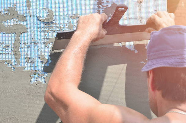 Πενήντα ετών χειρώνακτα με τοίχο σοβάτισμα εργαλεία ανακαίνιση σπιτιού. Γυψαδόρο ανακαίνιση τοίχους και γωνίες με σπάτουλα και γύψο. Εγκατάσταση τοίχου πολτού. Εργασίες κατασκευής και φινιρίσματος - Φωτογραφία, εικόνα