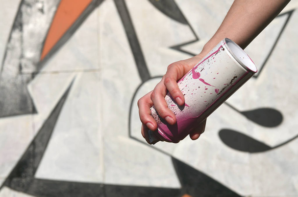 Фотографія руки дівчини з аерозольною фарбою банок в руках на фоні графіті стіни. Концепція вуличного мистецтва та використання аерозольних фарб. Фонове зображення художнього магазину Graffiti
 - Фото, зображення
