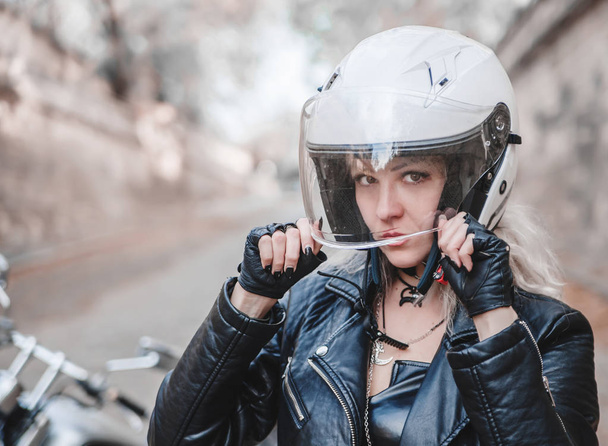 Beautiful biker woman posing with motorcycle on the road.  - Photo, image