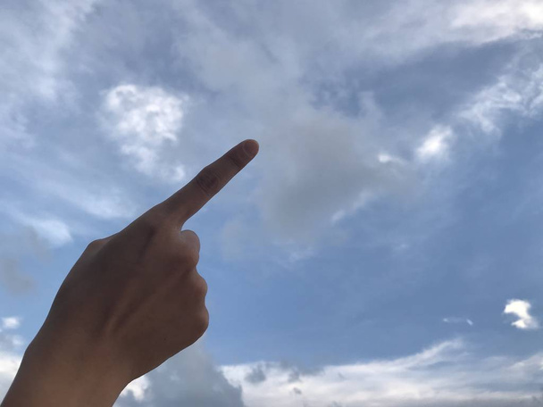 Kobieta za pomocą jej prawym palcem wskazującym skierowaną w górę w jasne błękitne niebo z białego obłoku w dzień - Zdjęcie, obraz