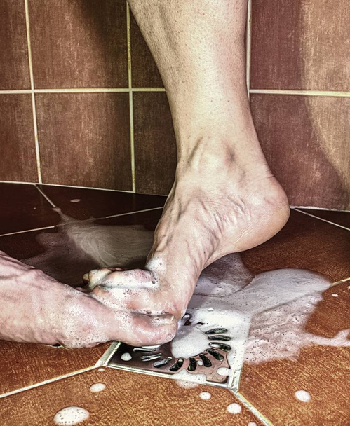 Para dorosłych gry prysznicem, Nagie stopy na wiejskich uprawiali podłogi. Romantyczny motyw. - Zdjęcie, obraz