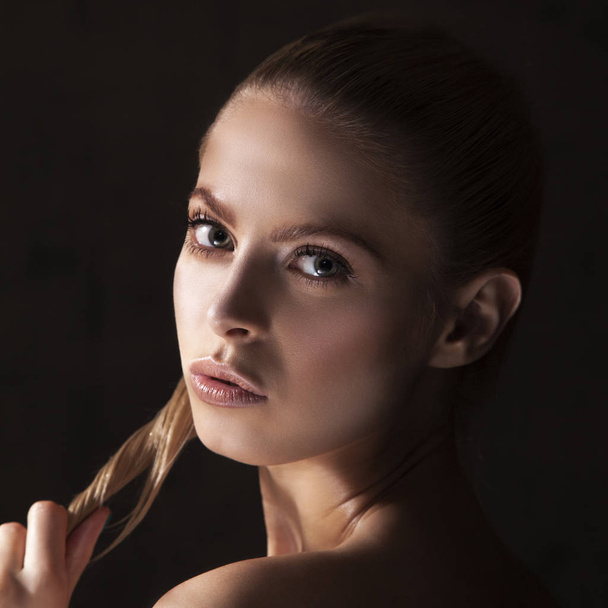 Retrato de primer plano de modelo con maquillaje natural posando sobre fondo negro
 - Foto, Imagen