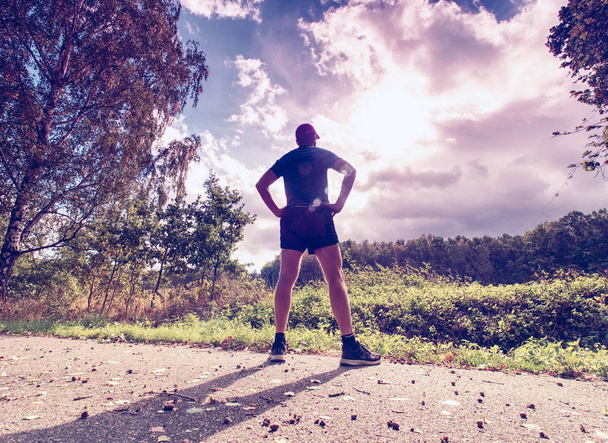 Runner park yolda germe. Terli kıyafetler bizzat koşu, günbatımı karşı flare - Fotoğraf, Görsel