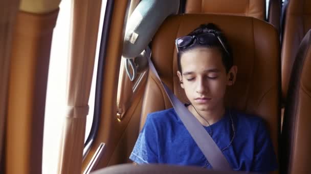 Concept van de zomervakantie, reizen. tiener jongen rijdt in een minibus met koptelefoon. - Video