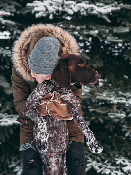 Mujer jugando con su perro en el bosque nevado
 - Foto, imagen