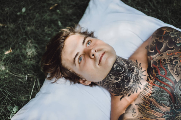 handsome young man in tattoos relaxing in bed  - Photo, image