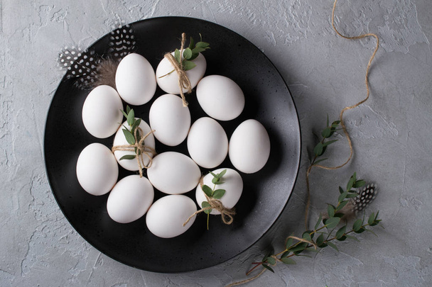 White chicken raw  eggs on a black plate. Top view and copy space. Easter  photo concept. - Foto, Imagem