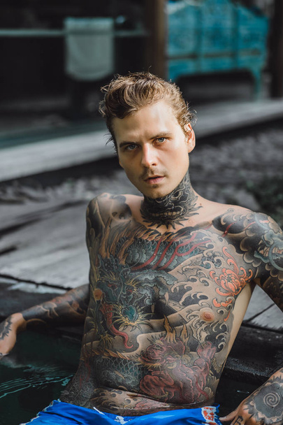 young handsome man in tattoos resting in the outdoor pool. A tattooed man in the pool is having fun. on bali, indonesia - Foto, Imagem