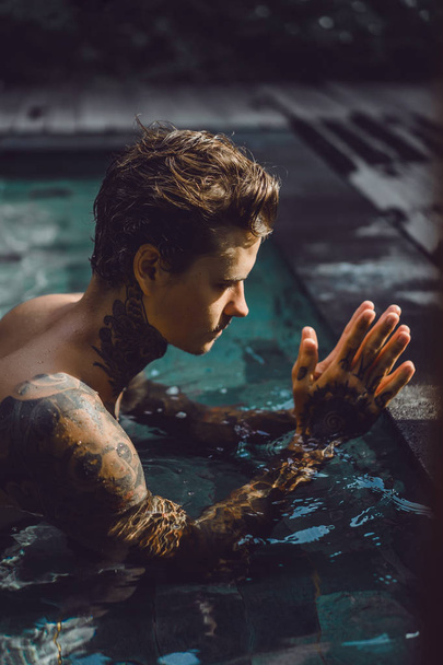 giovane bell'uomo tatuato che riposa nella piscina all'aperto. Un uomo tatuato in piscina si sta divertendo. su bali, indonesia
 - Foto, immagini