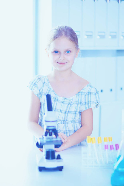 Schoolgirl looking through microscope in science class. - Valokuva, kuva