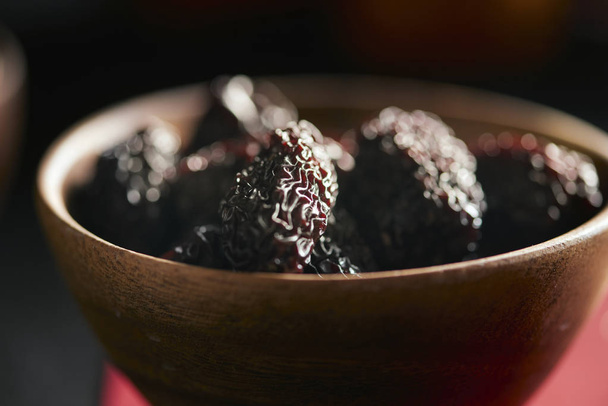 Nahaufnahme von getrockneten Früchten in Schale auf dunklem Hintergrund - Foto, Bild