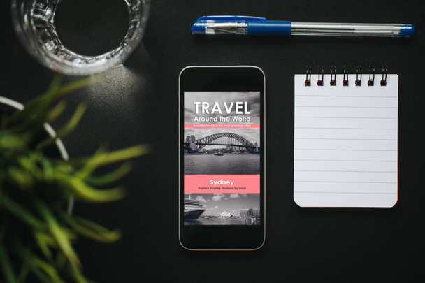 Travel news website in a smartphone screen on a black table. - Foto, imagen