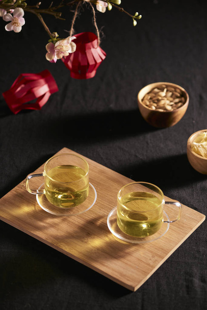 Comida y bebida de año nuevo lunar en mesa de madera oscura con rama de cerezo en flor
 - Foto, imagen