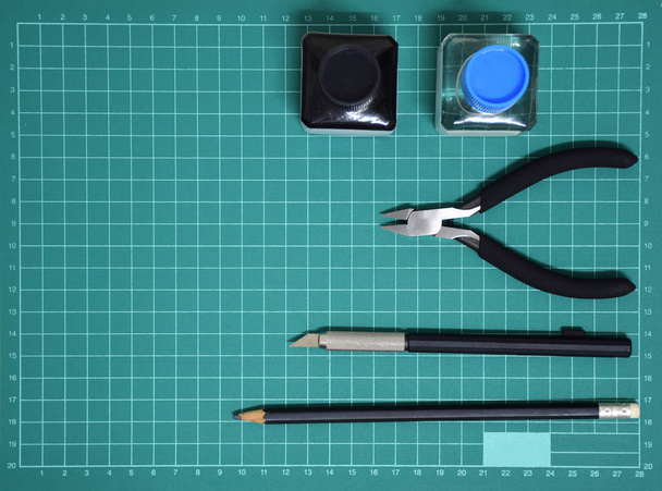 Vista superior Kit de herramientas de plástico modelo tinta, cuchillo de arte, alicates de corte en la estera de corte y espacio de copia
 - Foto, Imagen
