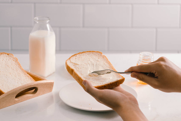 mani umane che spalmano burro su fetta di pane, primo piano
 - Foto, immagini