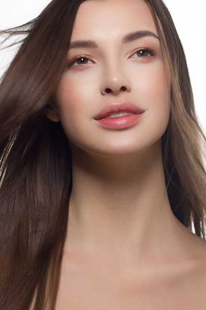 Close-up of beauty girl with long straight developing hair and radiant daytime makeup on her face. Skin care natural cosmetics in the spa salon or cosmetology. - Foto, Imagen
