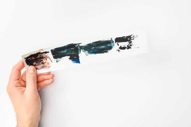 Man met papier met abstract aquarel penseelstreken ingesteld op witte achtergrond - Foto, afbeelding