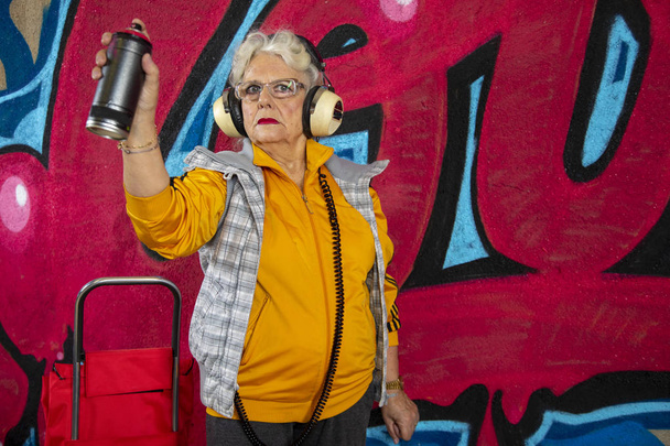 awesome rebel grandma graffiti artist against an urban wall - Photo, Image