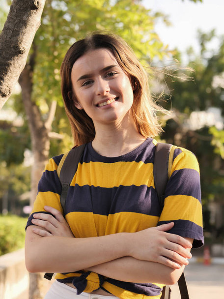 Portrait of teenager girl in campus with backpack and tree background. - Foto, afbeelding