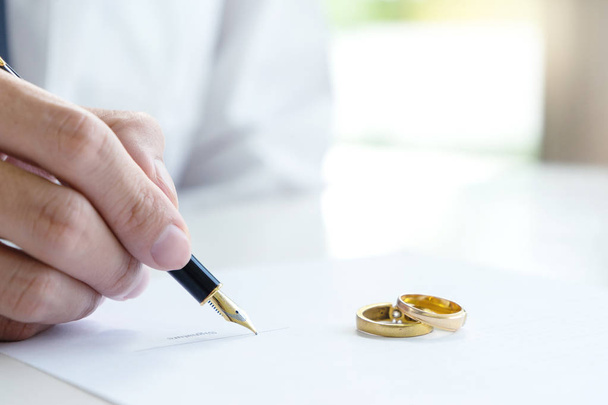 Hand man vrouw op papier met marry ring op papier te ondertekenen van huwelijk of echtscheiding - Foto, afbeelding