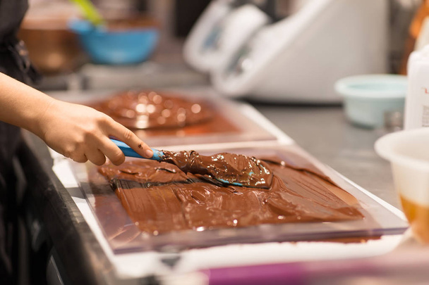 production, cooking and people concept - confectioner making chocolate sweets at confectionery shop - Foto, Imagen
