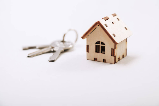Wooden miniature house with door keys close up. Real estate concept. Small toy wooden house with keys with copy space. - Foto, afbeelding
