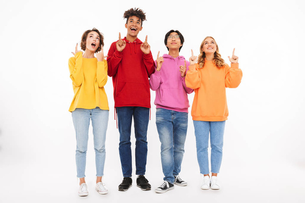 Group of cheerful teenagers isolated over white background, pointing up - Фото, зображення