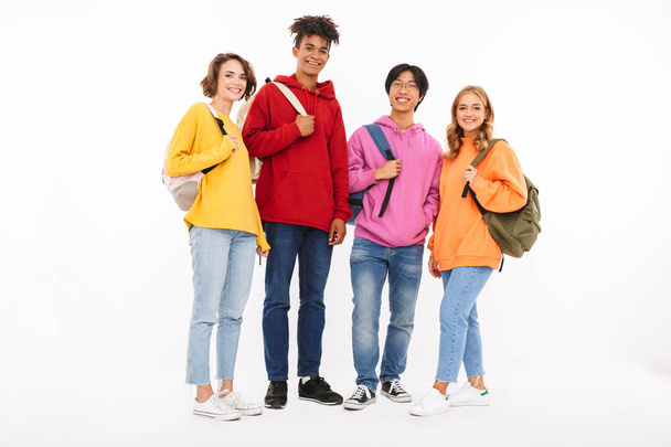 Group of cheerful teenagers isolated over white background, carrying backpacks, looking at camera - Photo, Image