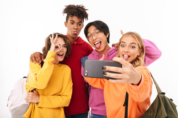 Groupe d'adolescents joyeux isolés sur fond blanc, portant des sacs à dos, prenant un selfie
 - Photo, image