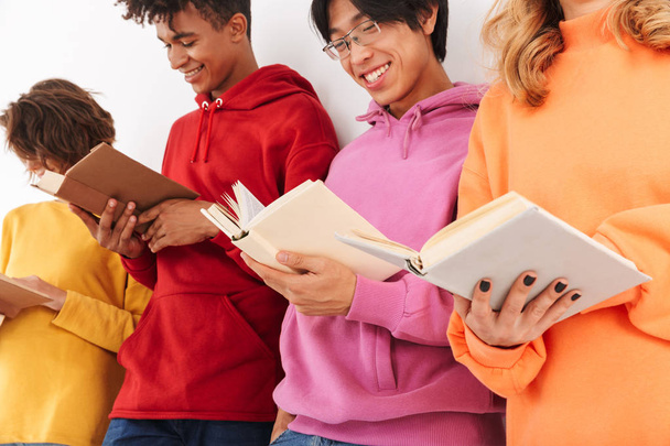 Group of cheerful smiling teenagers isolated over white background, reading books - Photo, image